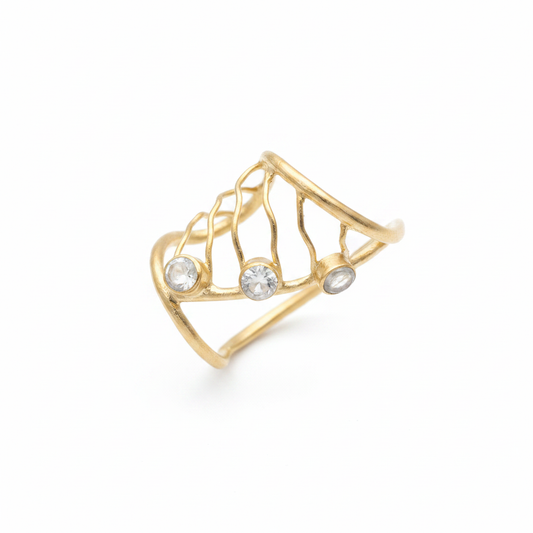 Anillo dorado abierto con diseño de red y tres piedras cristal sobre fondo blanco