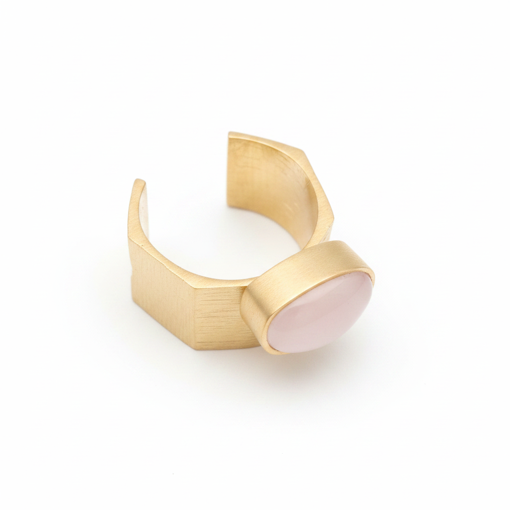 Anillo dorado con piedra rosa ovalada sobre fondo blanco